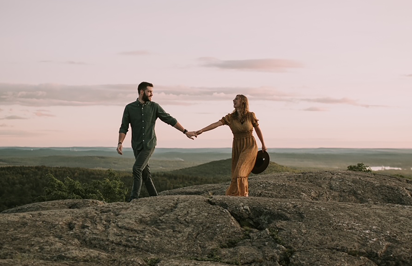 Mike and Kylee romantic photo walking on a mountain summit