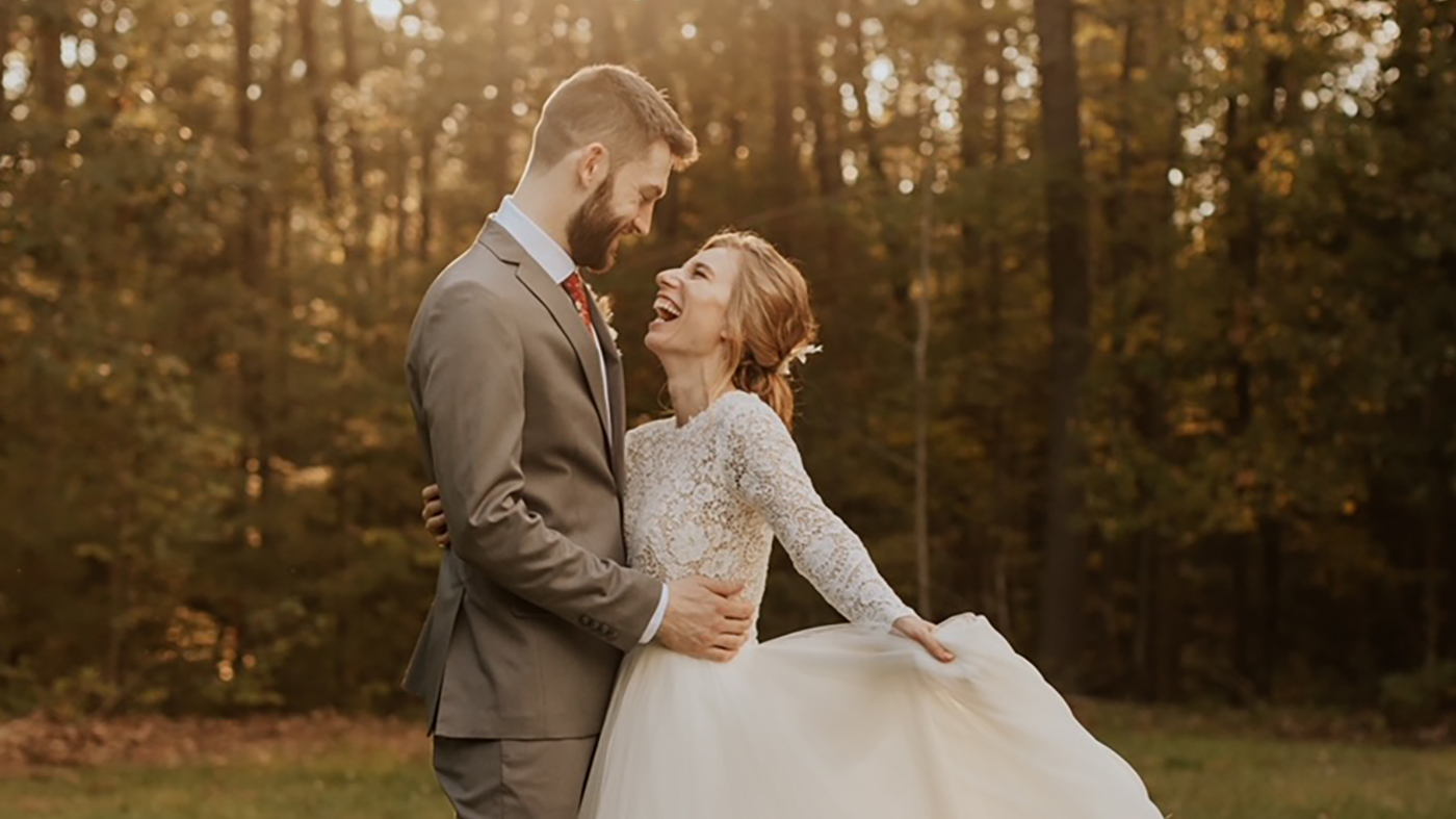 Mike and Kylee smiling at each other in a field on their wedding day