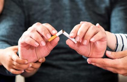 A person's hands, being supported by others, holding a broken cigarette
