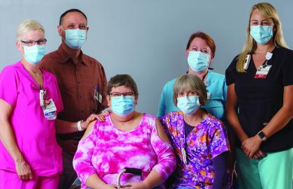 Kathy Tremblay, patient sits smiling, surrounded by her comprehensive inpatient rehabilitation care team