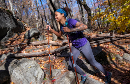 A woman hiking Monadnock with hiking poles & a smile on her face