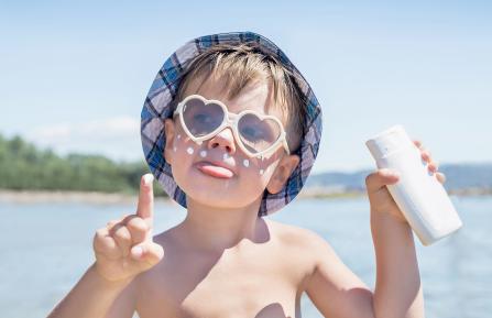 Young boy using sun protection, wearing sunglasses.