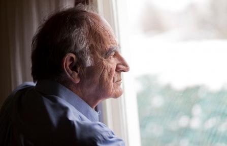 Senior man looking out a window
