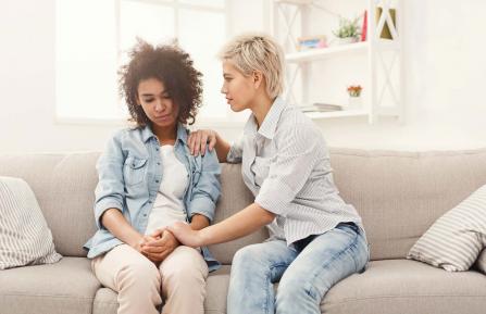 One woman talking to another woman while sitting on a couch