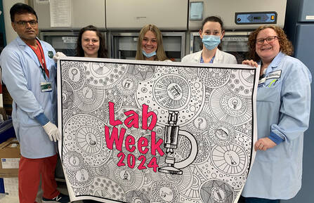 Lab staff hold a banner celebrating lab week