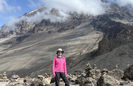 Hilary Brown, MSN, RN, a white woman, stands on a mountain