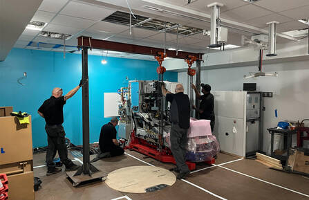 Workers stand next to a giant machine 