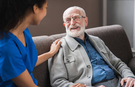 A dark skinned medical provider caring for an older white man