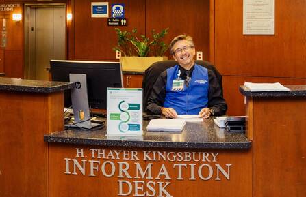 Michael Bell smiles broadly from behind the central information desk in Cheshire Medical Center's main lobby