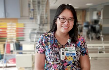 Young, female, asian rehab nurse with glasses, vocera and RN badge stands in the inpatient occupational therapy room