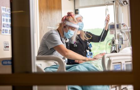 Two providers with a patient in a hospital bed