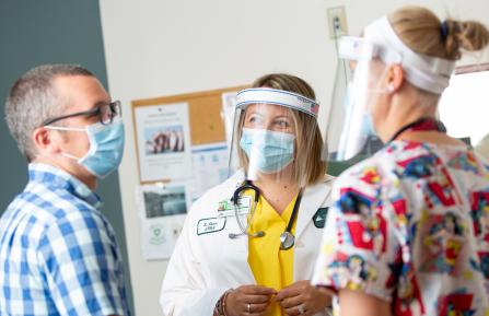 Two masked providers with adult masked patient