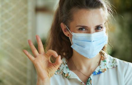 Smiling lady wearing a surgical mask with nose wire pinched in place properly