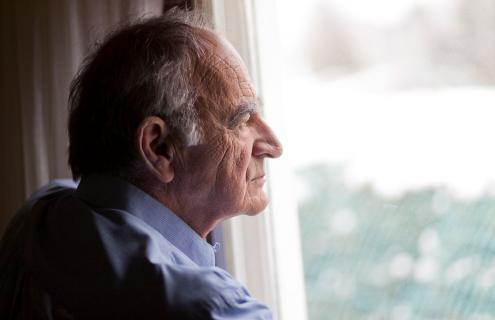 Senior man looking out a window