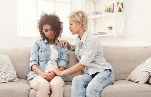 One woman talking to another woman while sitting on a couch