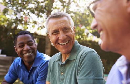 Three middle-aged culturally diverse men in conversation.