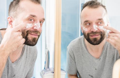 Man moisturizing face
