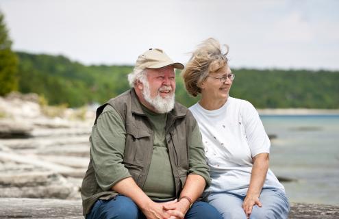 Older white couple sitting on rocky shore
