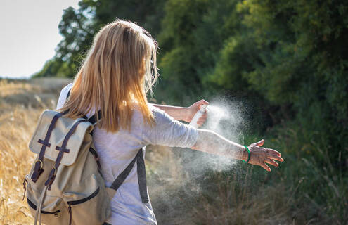 Hiker spraying herself for mosquitoes