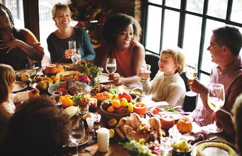 A child makes a toast with a class of water with their family around a laden holiday table