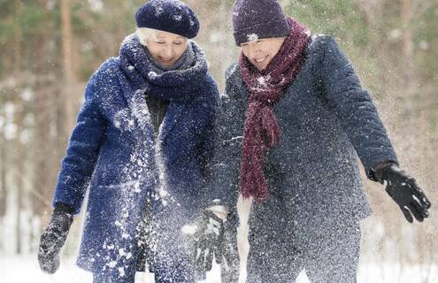 Two adults in winter gear looking happy and playful while on a walk in the snow