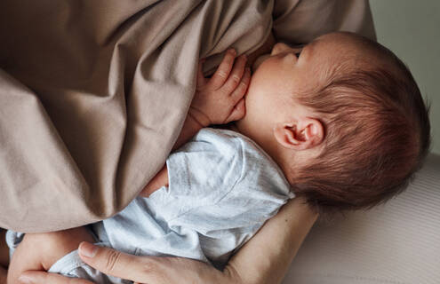 A baby nuzzles into their mother