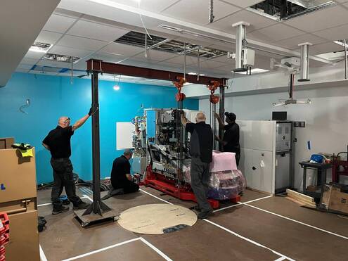 Workers stand next to a giant machine 