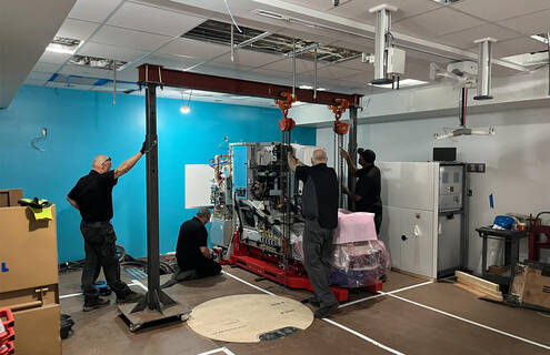 Workers stand next to a giant machine 