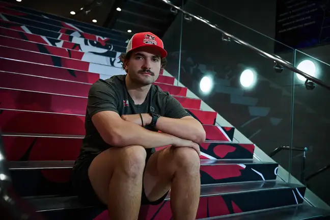 Man in gym clothing sits on bleachers