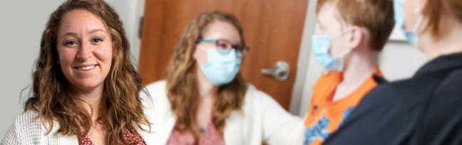 Julie Cookish, APRN smiles with a blurred image behind her of her caring for a child and parent.