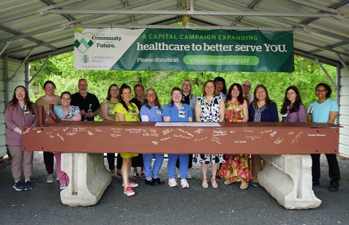 A group of people stand with a signed beam